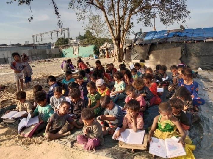 Children studying outdoors on mats in a community setting
